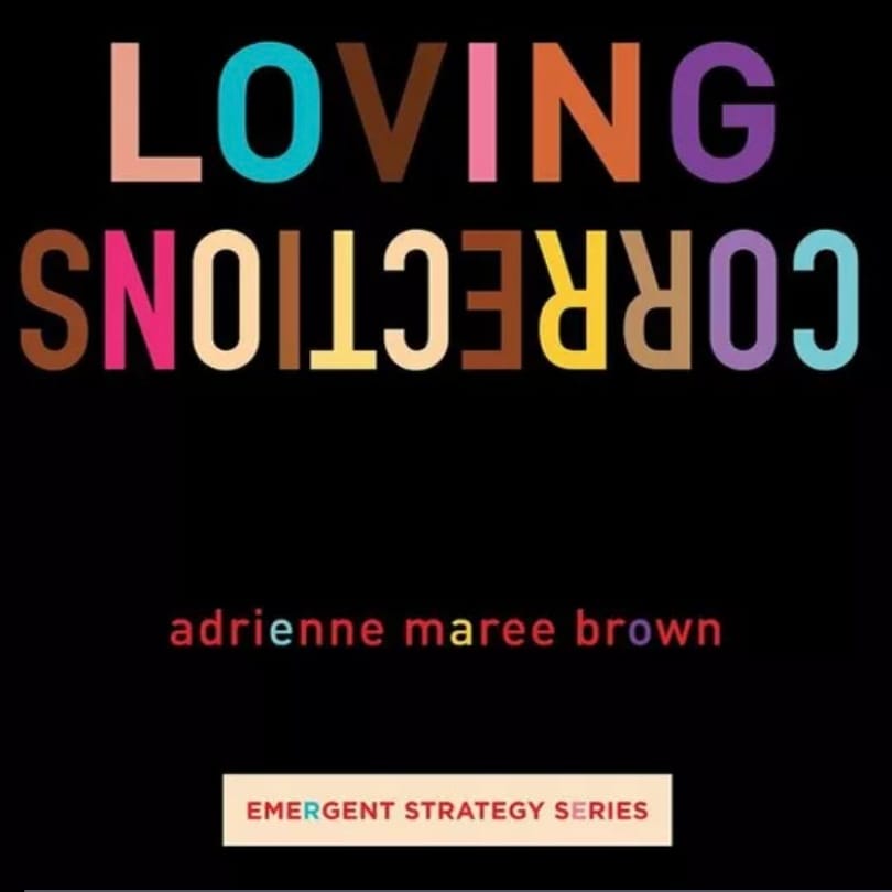 The image features an audiobook cover design with the title “Loving Corrections” written in bold, colorful title text with capitalized letters; the word ‘corrections’ is shown as a backwards reflection. The author’s name, “Adrian Marie Brown” is below the title in bright red letters, and one different colored vowel in each word. Below the authors name is the text “Emergent Strategy Series.” The background of the image is solid black.